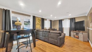 A modern living room with a sofa set, a dining table with chairs, a TV, and a kitchen area visible through a glass door. - Forget your worries in this spacious and serene space. (Miami)