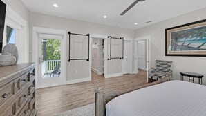 Un dormitorio con cama, cómoda, silla, ventilador de techo y un cuadro en la pared.