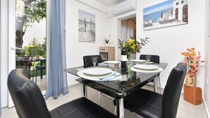 A dining area with a glass table, black chairs, and a vase of flowers. - Welcoming Apartment With Garden (Porec)