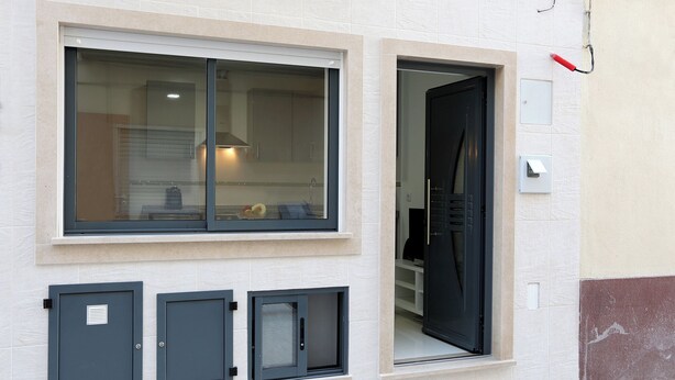 A building facade with a large window, a door, and three electrical boxes. - T1-Sunset Apartment (Nazaré)