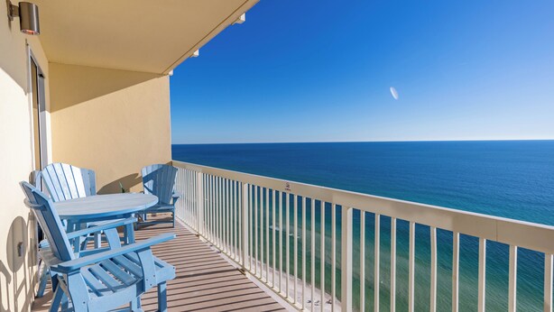 Varanda com vista para o oceano, com uma mesa e cadeiras.