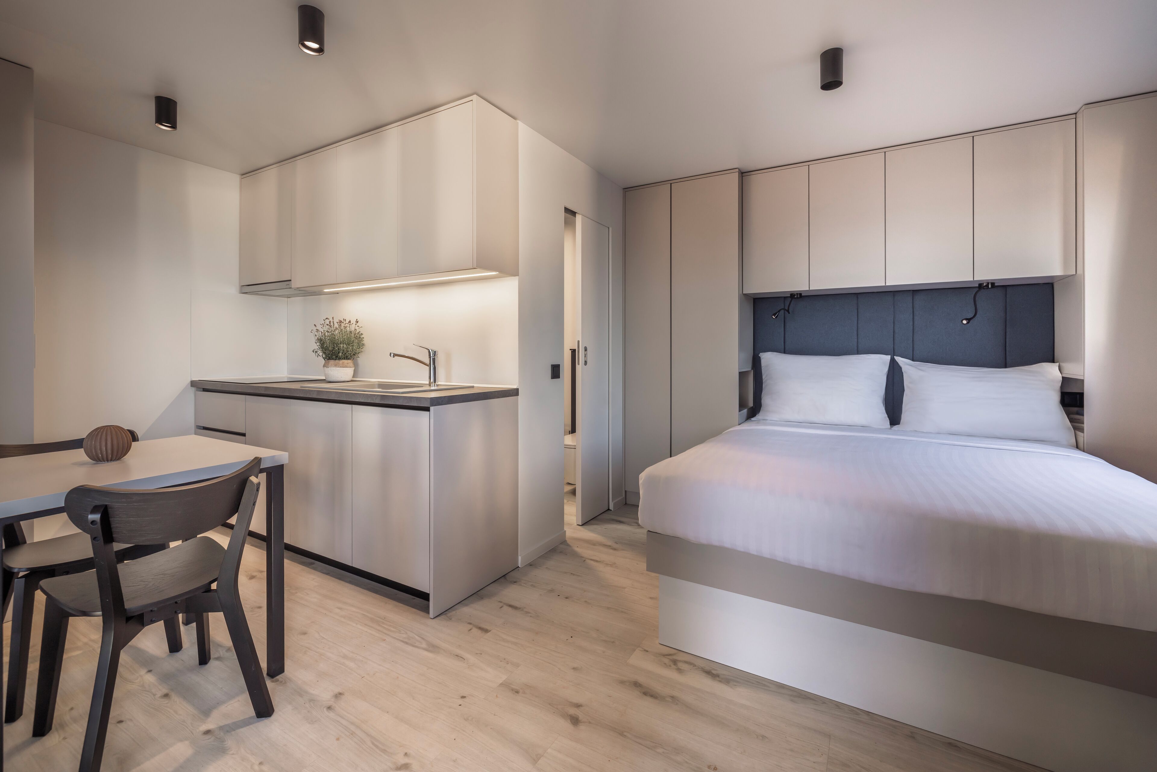 Een moderne slaapkamer met een groot bed, een nachtkastje en een inbouwkantoor met een stoel.