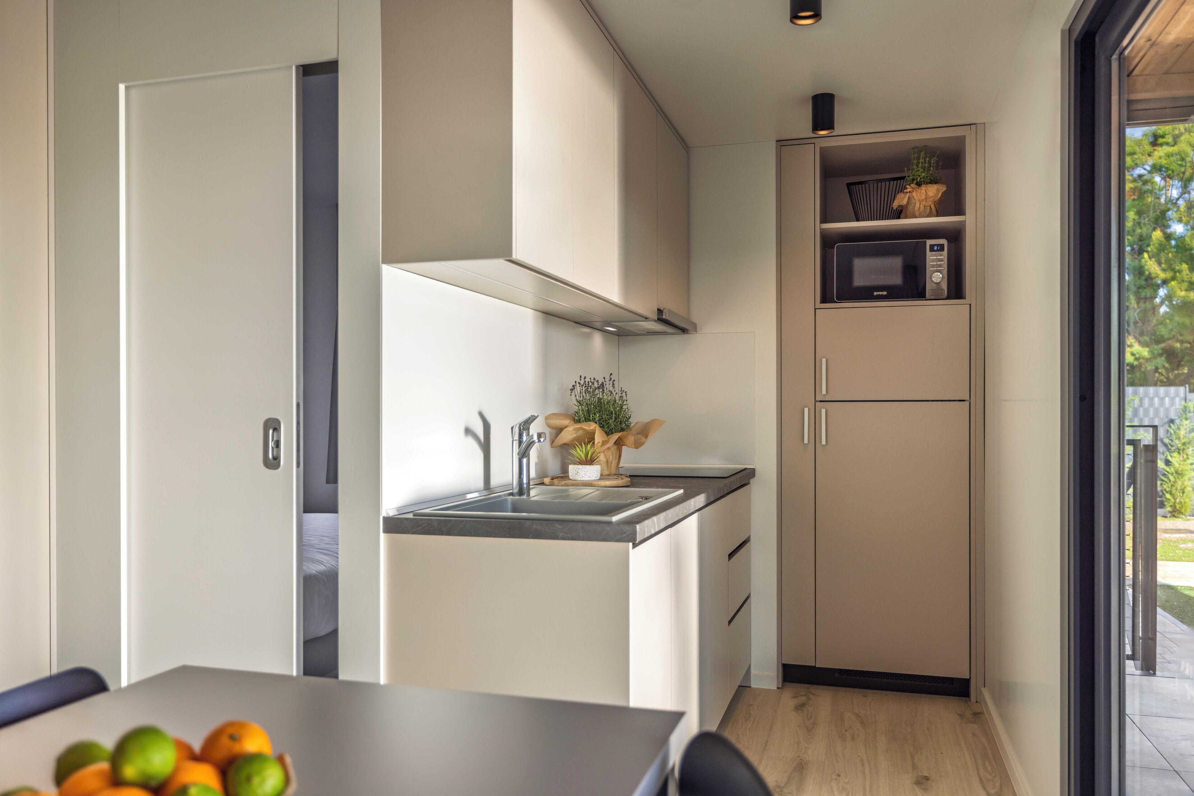 Una cocina compacta con microondas integrado, una pequeña encimera y un armario de madera.