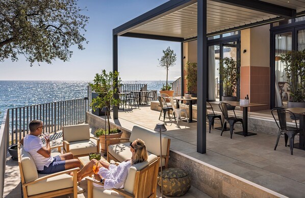 A modern outdoor seating area with a view of the sea, featuring wooden furniture and potted plants. - Maistra Camping Koversada Covered Mobile homes (Vrsar)