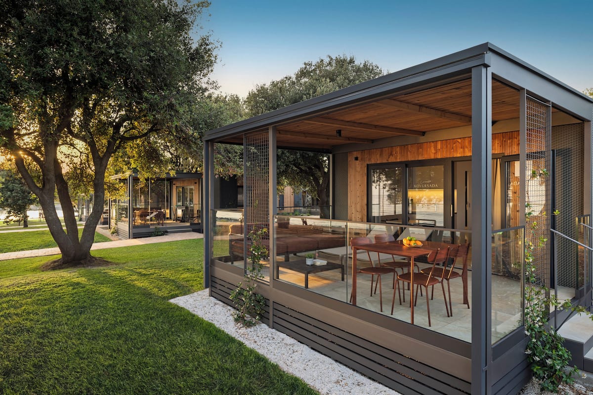Une maison moderne dotée d’un patio entièrement vitré, d’un coin repas et d’une terrasse en bois.