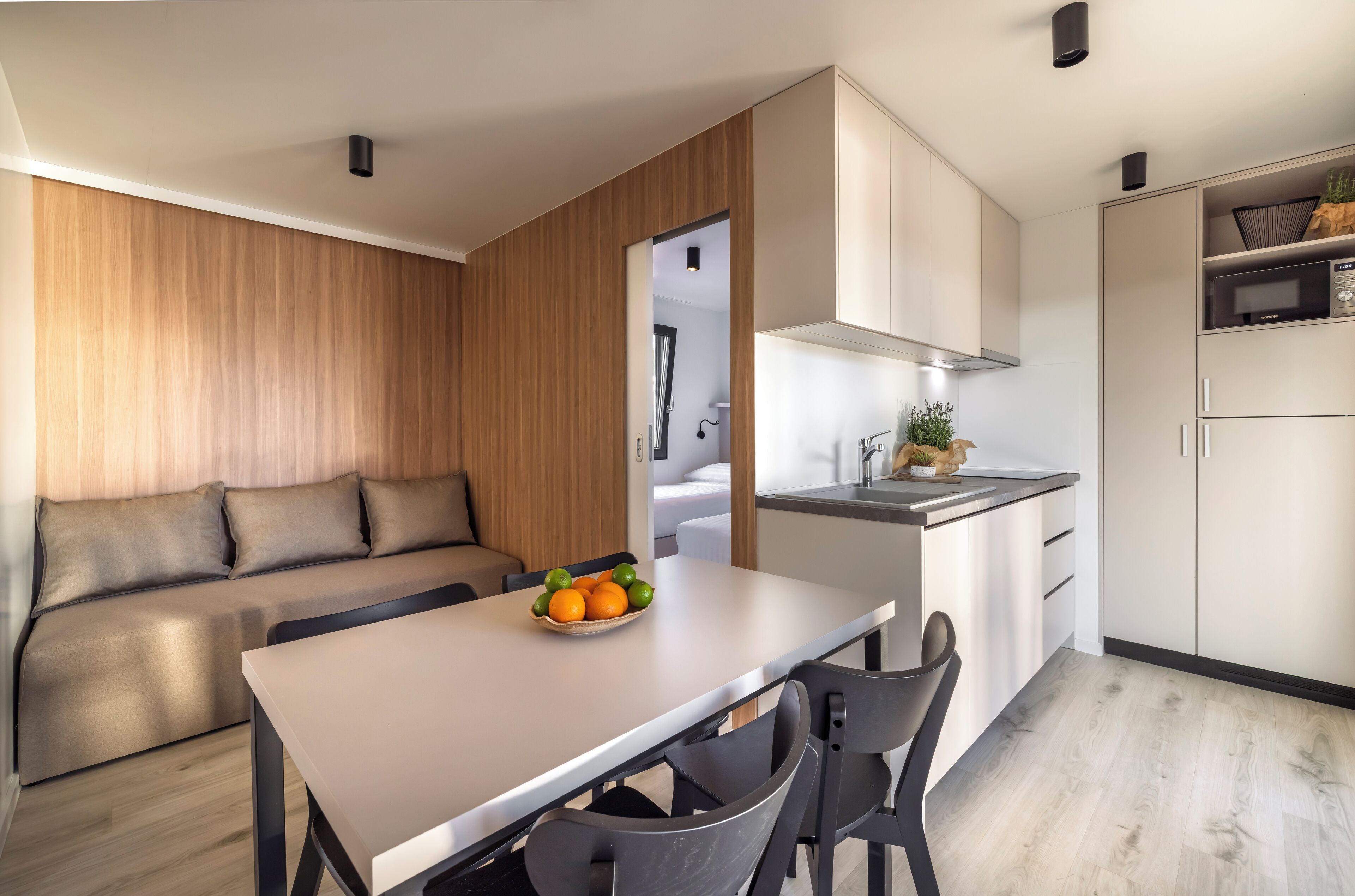 A modern kitchen with a dining area, wooden paneling, and a built-in microwave.