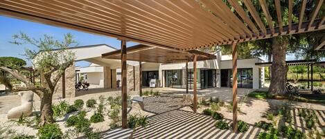 A modern outdoor area with a pergola, stone sculptures, and a paved walkway.