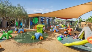 An outdoor play area with colorful play structures and seating.