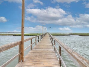 A wooden pier extending into calm water with a clear sky above.
