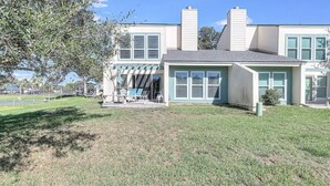 A two-story house with a front porch, a lawn, and a tree. - Bayfront Shores RRYC47 (Rockport)