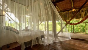 A bed with a canopy, wooden flooring, and a view of greenery outside. - Birds Eye View  (Armenia)
