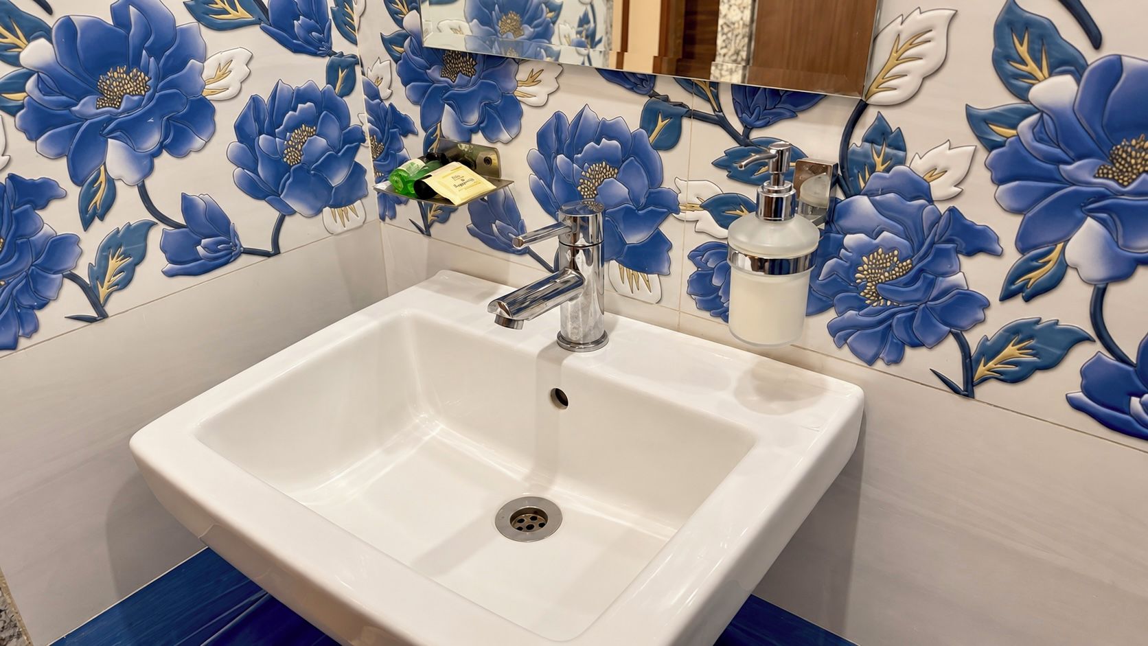 A bathroom with a white sink, a chrome faucet, and a mirror above it.