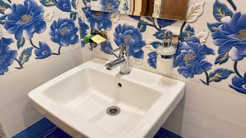 A bathroom with a white sink, a chrome faucet, and a mirror above it.