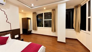 A hotel room with a bed, a wardrobe, a window with curtains, and a nightstand. - KALAKAR HAVELI - Udaipur (Udaipur)