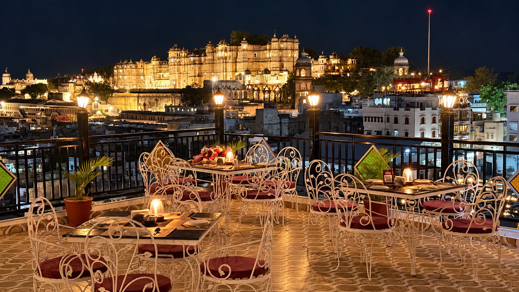 An outdoor dining area with metal chairs and tables, overlooking a historic building complex.