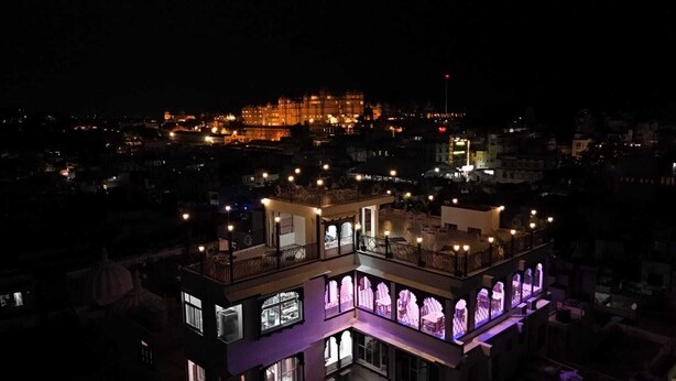 A multi-story building with balconies and illuminated windows at night.