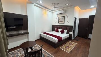 A bedroom with a bed, a TV, a desk, and a chair.