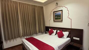 A hotel room with a large bed, a headboard with a picture, a nightstand, a carpet, and a ceiling with decorative patterns.