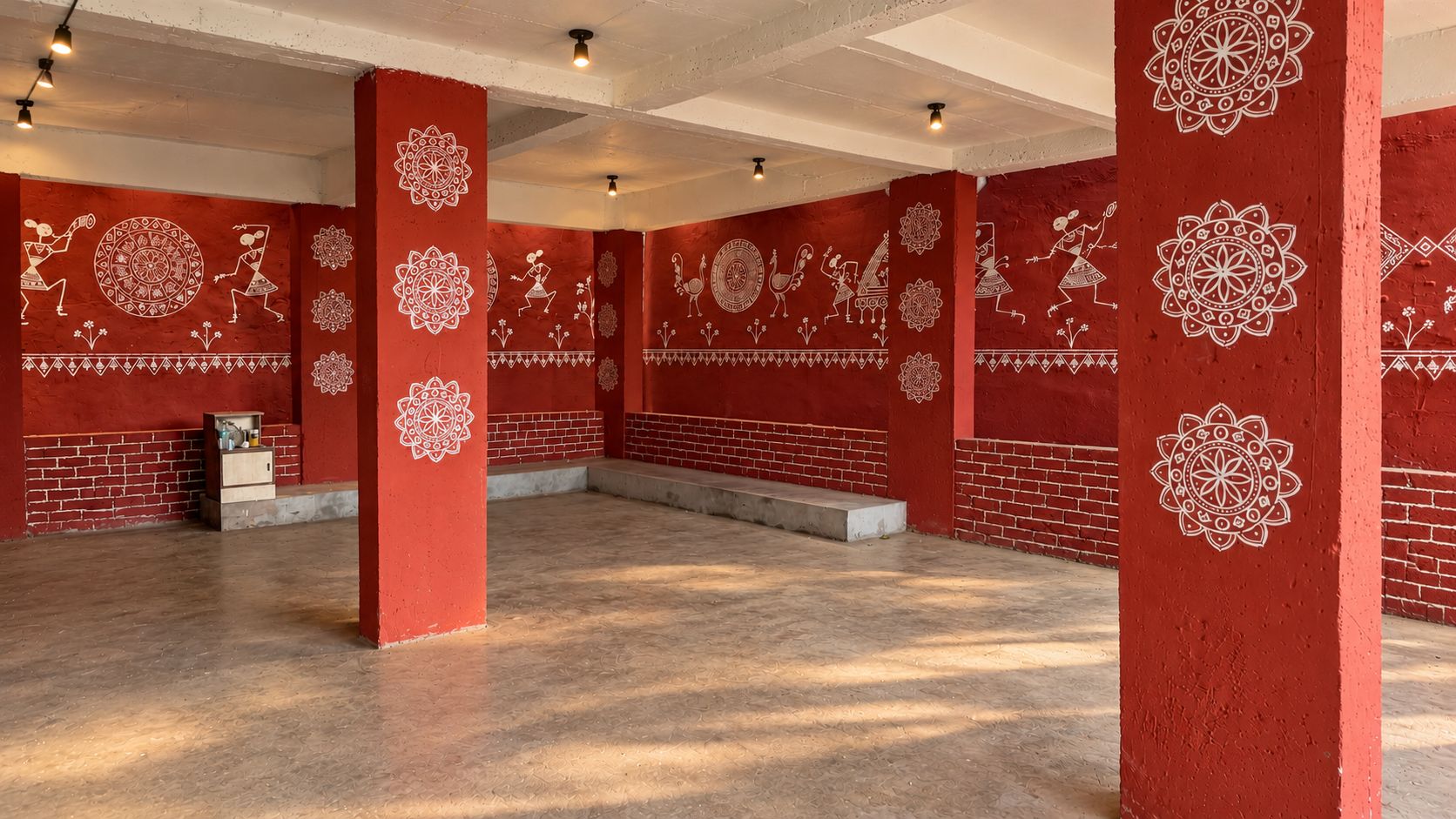 A spacious room with red walls and white patterns, featuring a brick wall and a small cabinet.