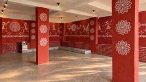 A spacious room with red walls and white patterns, featuring a brick wall and a small cabinet. - KALAKAR HAVELI - Udaipur (Udaipur)