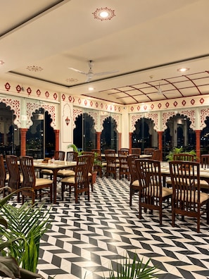 A restaurant with a checkered floor, wooden chairs, and tables. - KALAKAR HAVELI - Udaipur (Udaipur)