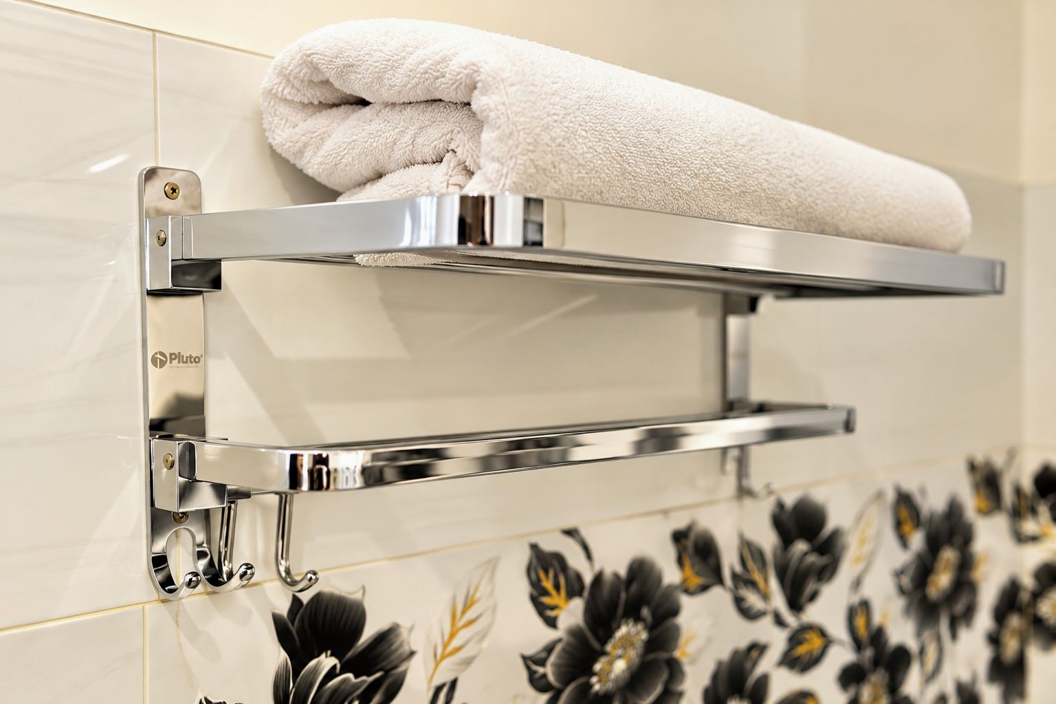 A bathroom with a towel rack mounted on a tiled wall, a towel hanging on it, and a floral tile pattern below.
