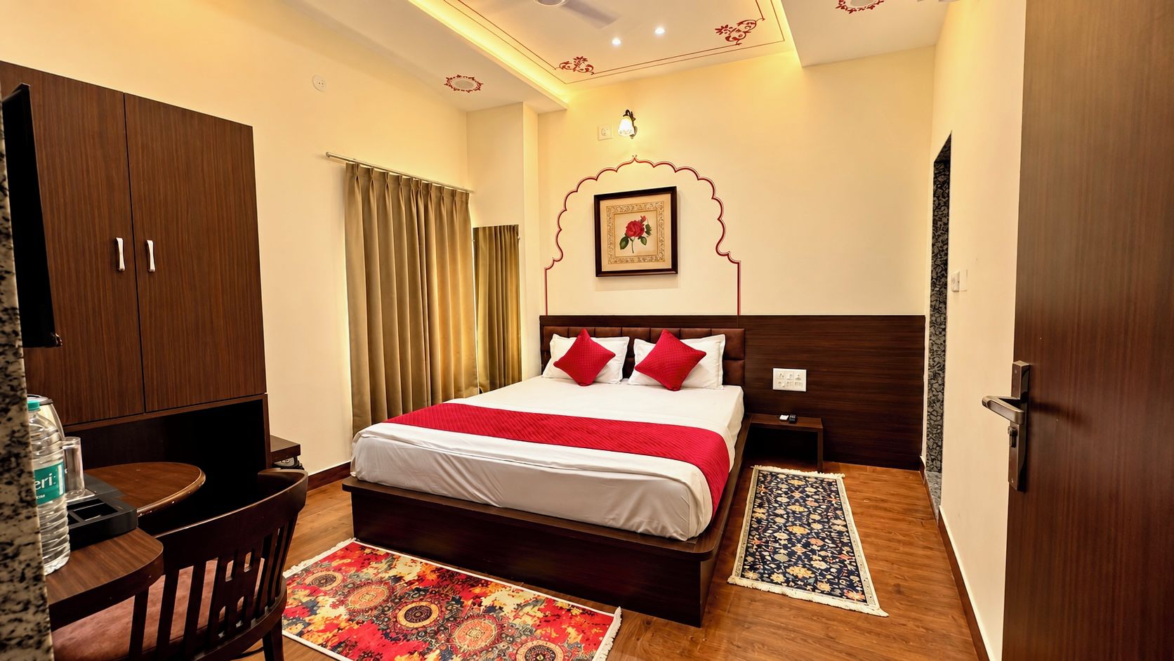 A hotel room with a bed, a desk, a chair, a wardrobe, and a bathroom.