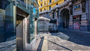 A building with a glass facade, a metal entrance, and a tiled ground. - Terrazzo Panoramico su Napoli by Wonderful Italy (Napoli)