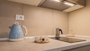 Moderni keittiö, jossa on sininen vedenkeitin, kahvinkeitin ja kaksi kuppia työtasolla.