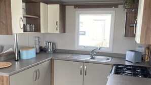 Una cocina compacta con estufa integrada, un lavamanos y armarios de madera.