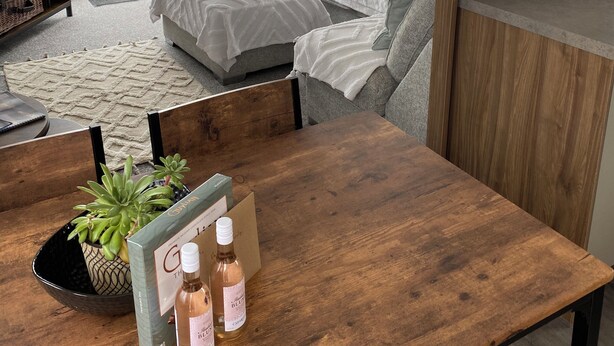 Una sala de estar moderna con un sofá, una mesa de comedor de madera y un ventanal grande.