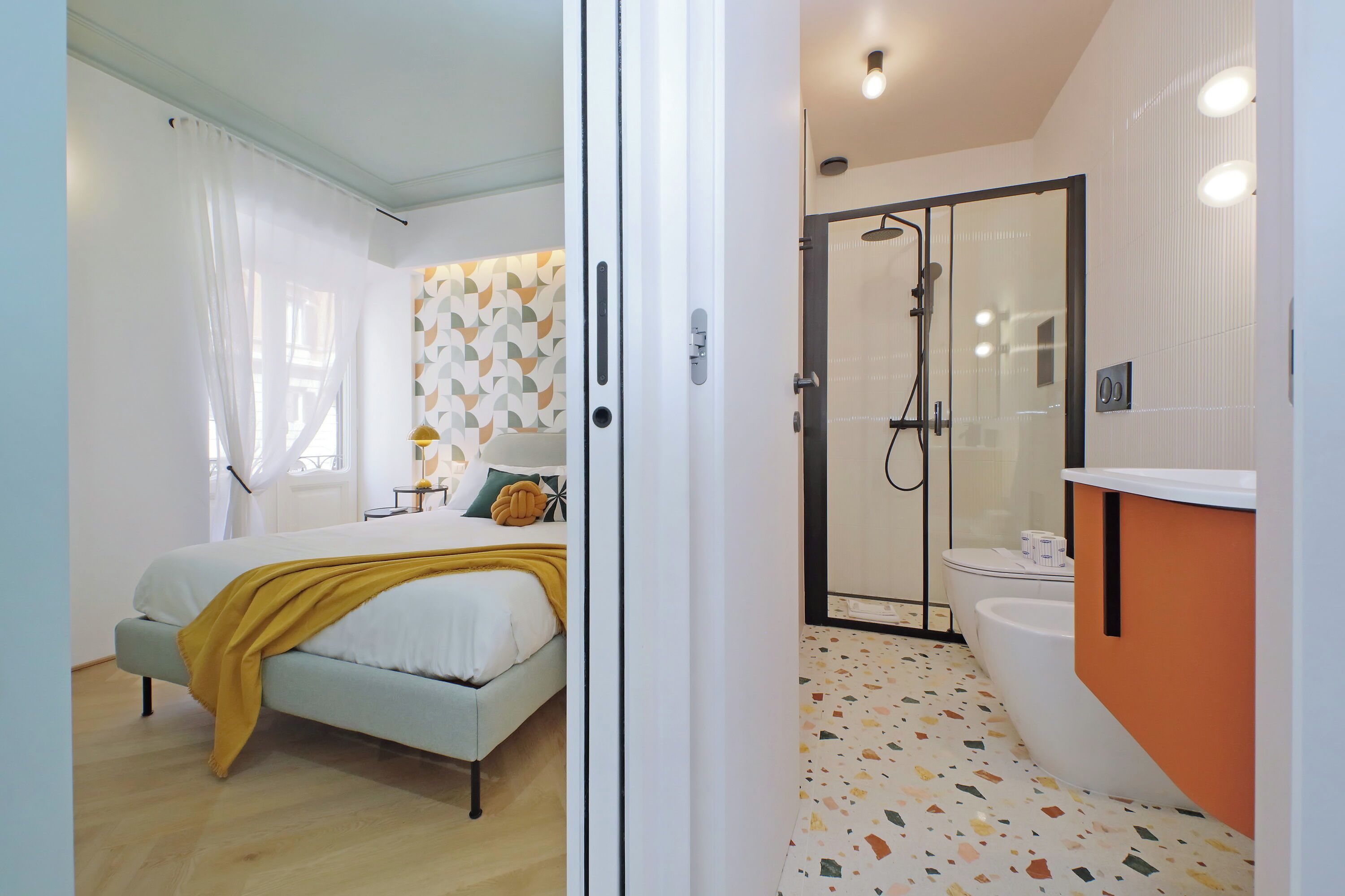 A bedroom with a bed, a bedside table, and a window with curtains.