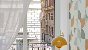 Une vue par la fenêtre donnant sur une rue, avec un mur orné de motifs et un lampadaire jaune.