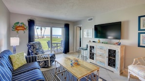 A living room with a sofa, coffee table, TV, and a view of the outdoors.