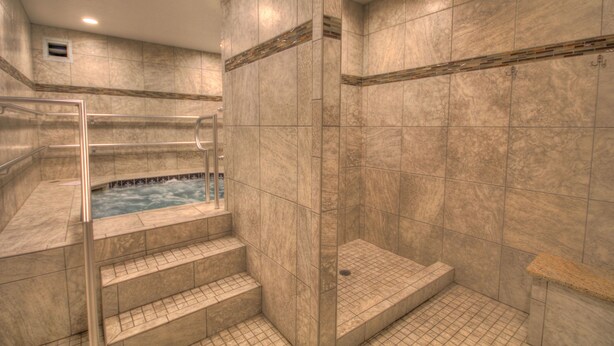 A spa area with a hot tub, a glass-enclosed shower, and a tiled floor.
