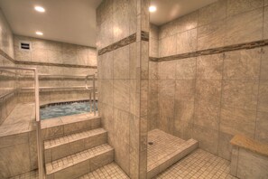 Ein Wellnessbereich mit Whirlpool, einer gläsernen Dusche und gefliestem Boden.