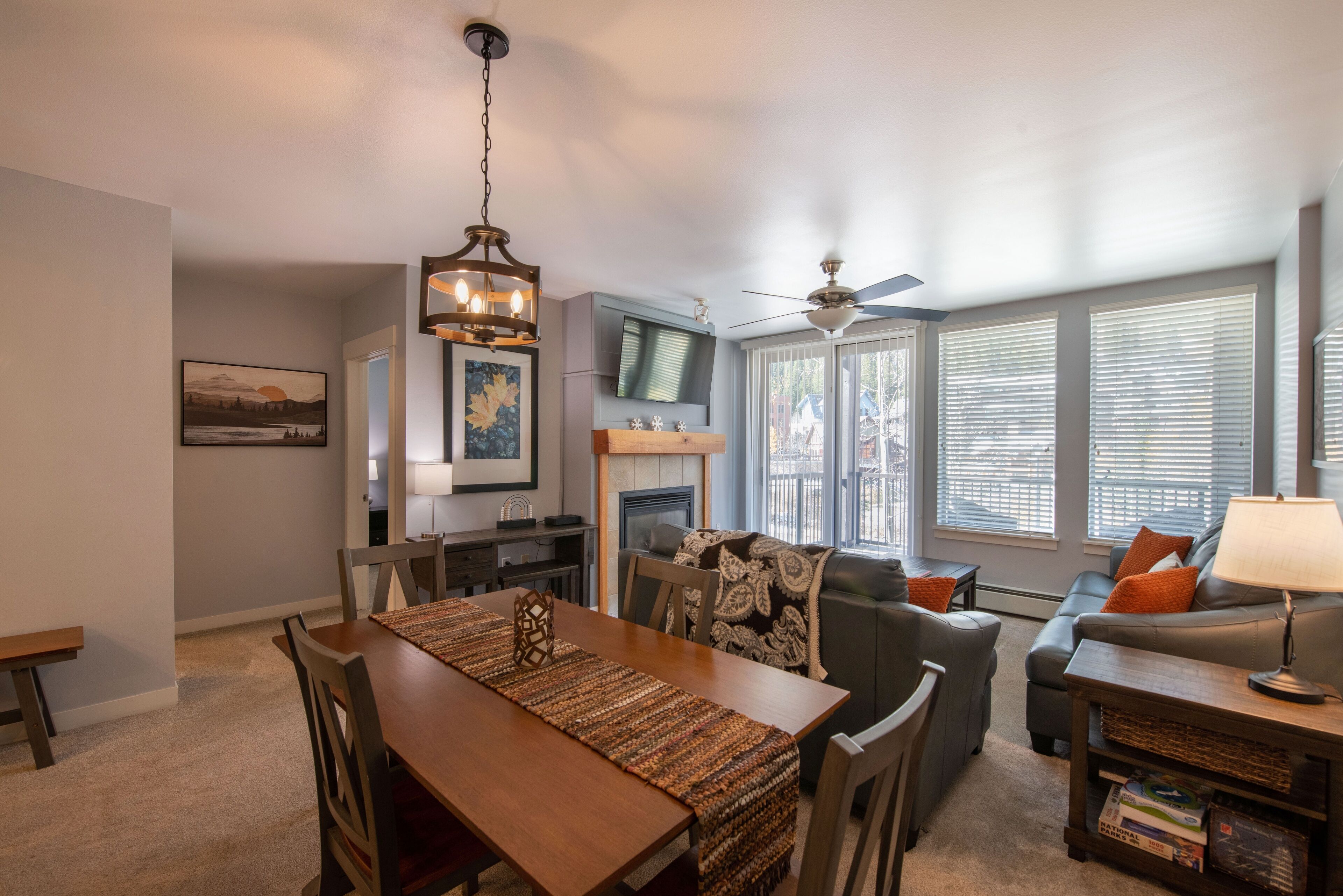 A dining area with a wooden table and chairs, a fireplace, a television, and a sofa with cushions.