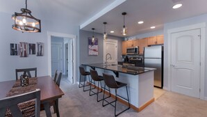 A modern kitchen with a central island, bar stools, and pendant lighting. - Premium Unit 4285 Fraser Crossing/founders Pointe 2 Bedroom Condo (Winter Park)