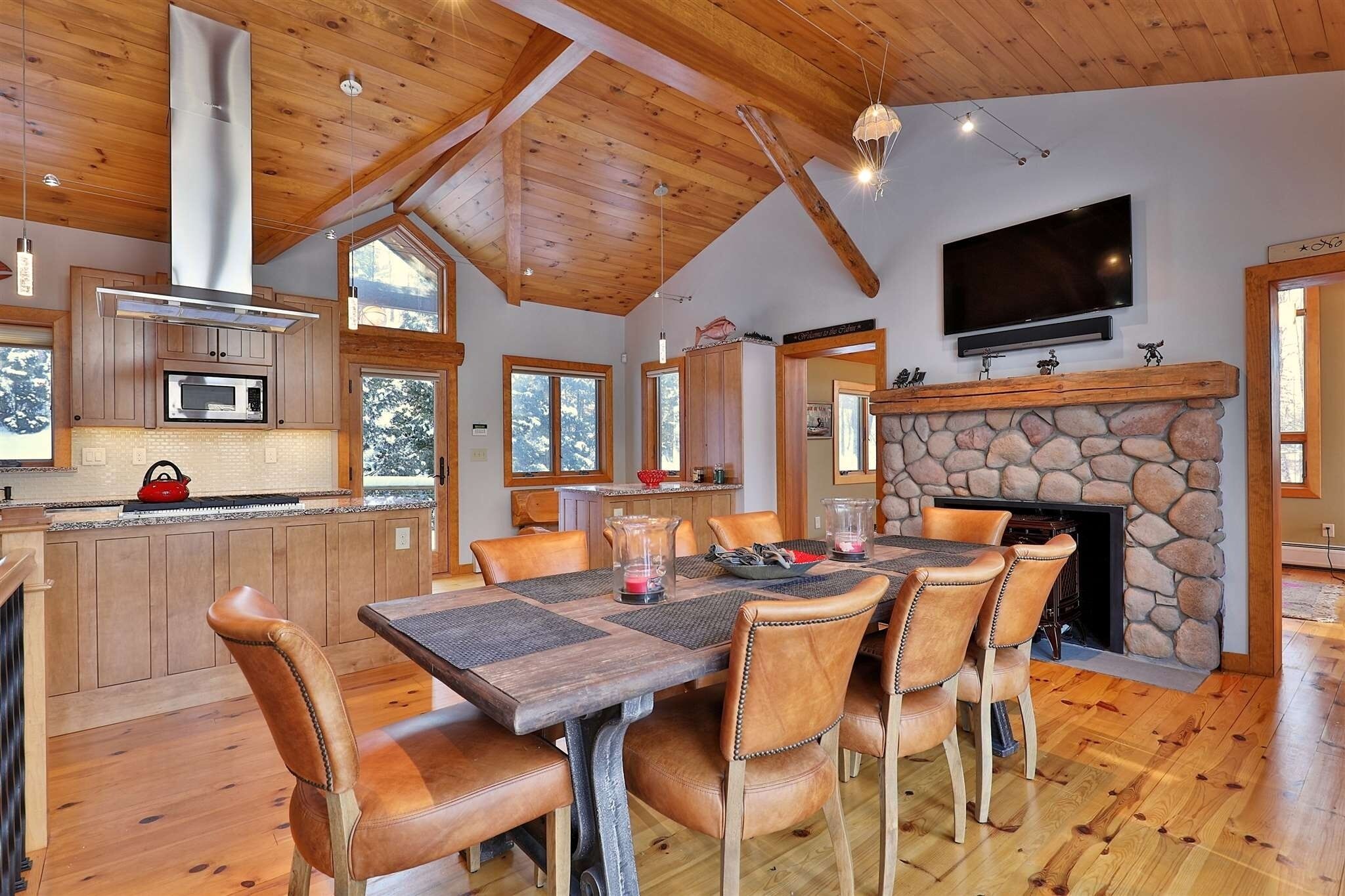 A spacious kitchen with wooden cabinets, a microwave, and a stone fireplace.