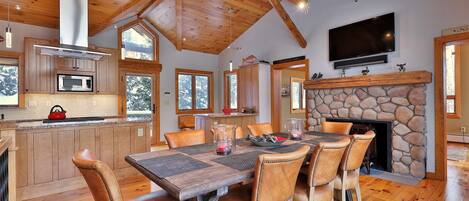A spacious kitchen with wooden cabinets, a microwave, and a stone fireplace.