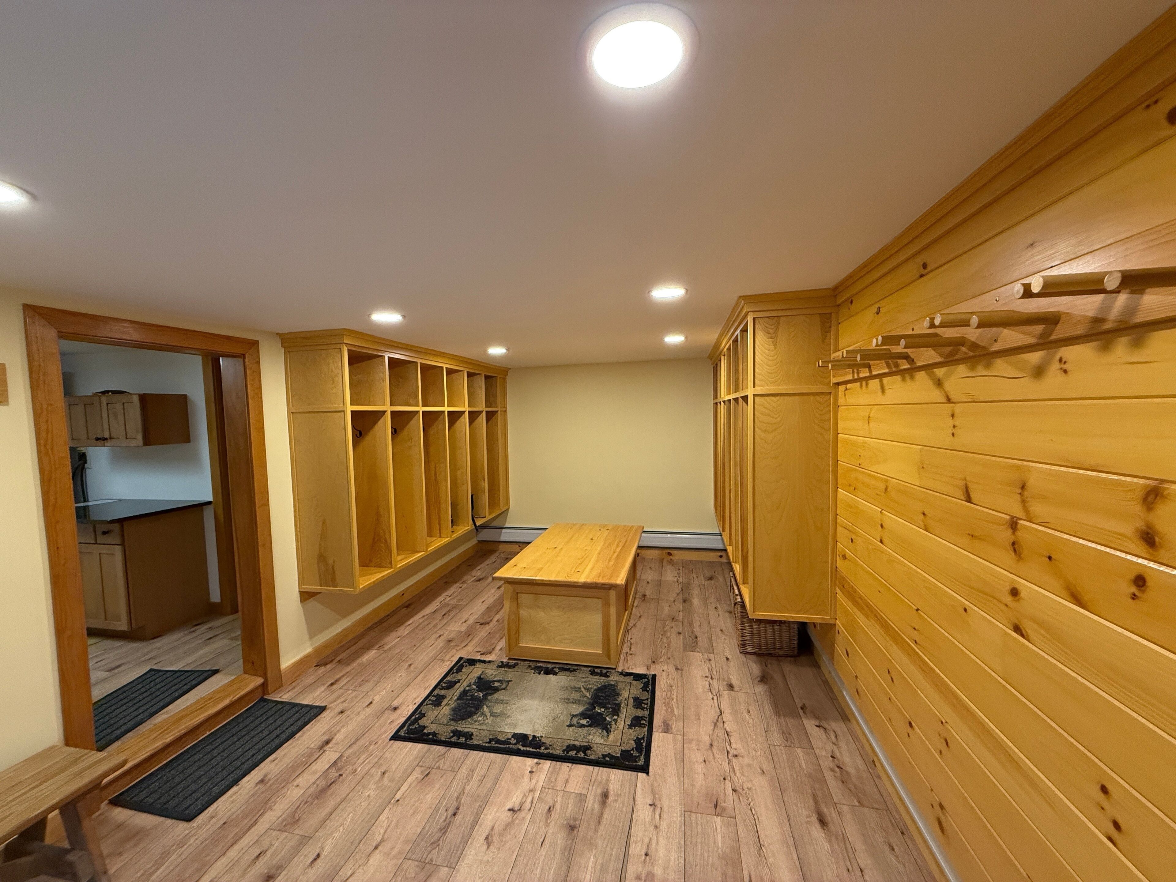 A room with wooden walls, a wooden bench, a small rug, and built-in wooden cabinets.