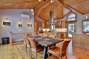 Un interior de madera con zona de comedor, cocina y ventanas amplias.