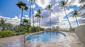 A swimming pool with a stone deck, surrounded by palm trees and a clear sky. - Kamaole Nalu, #405 2 Bedroom Condo (Kihei)