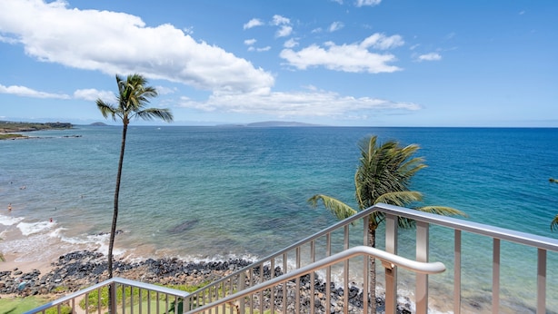 A coastal view with clear skies, a staircase leading to a balcony overlooking the sea, and a palm tree. - Kamaole Nalu, #405 2 Bedroom Condo (Kihei)