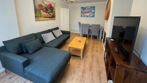 A living room with a sofa, coffee table, TV, and a painting on the wall. - Lovely 2 Bedrooms Flat in South Sutton (Sutton)