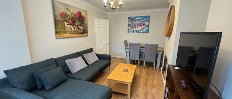 A living room with a sofa, coffee table, TV, and a painting on the wall.