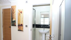 A bathroom with a white sink, a glass shower enclosure, and wooden doors.