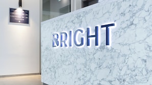 A marble reception desk with illuminated 'BRIGHT' sign, directional sign above, and a clean, modern interior. - BRIGHT Schloß Holte-Stukenbrock (Schloss Holte-Stukenbrock)