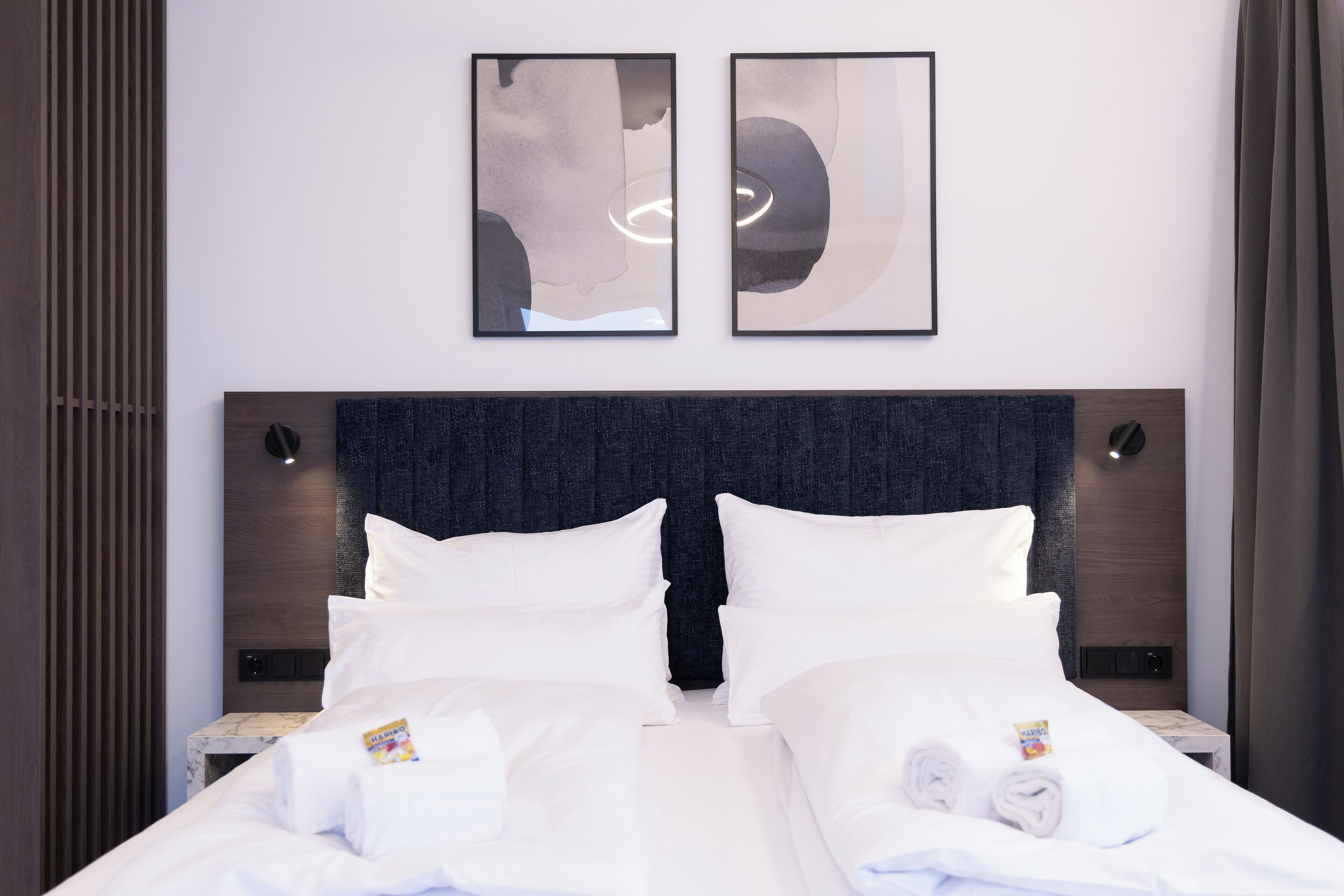 Une chambre d’hôtel avec un grand lit, deux tables de chevet et une œuvre d’art abstraite accrochée au mur.