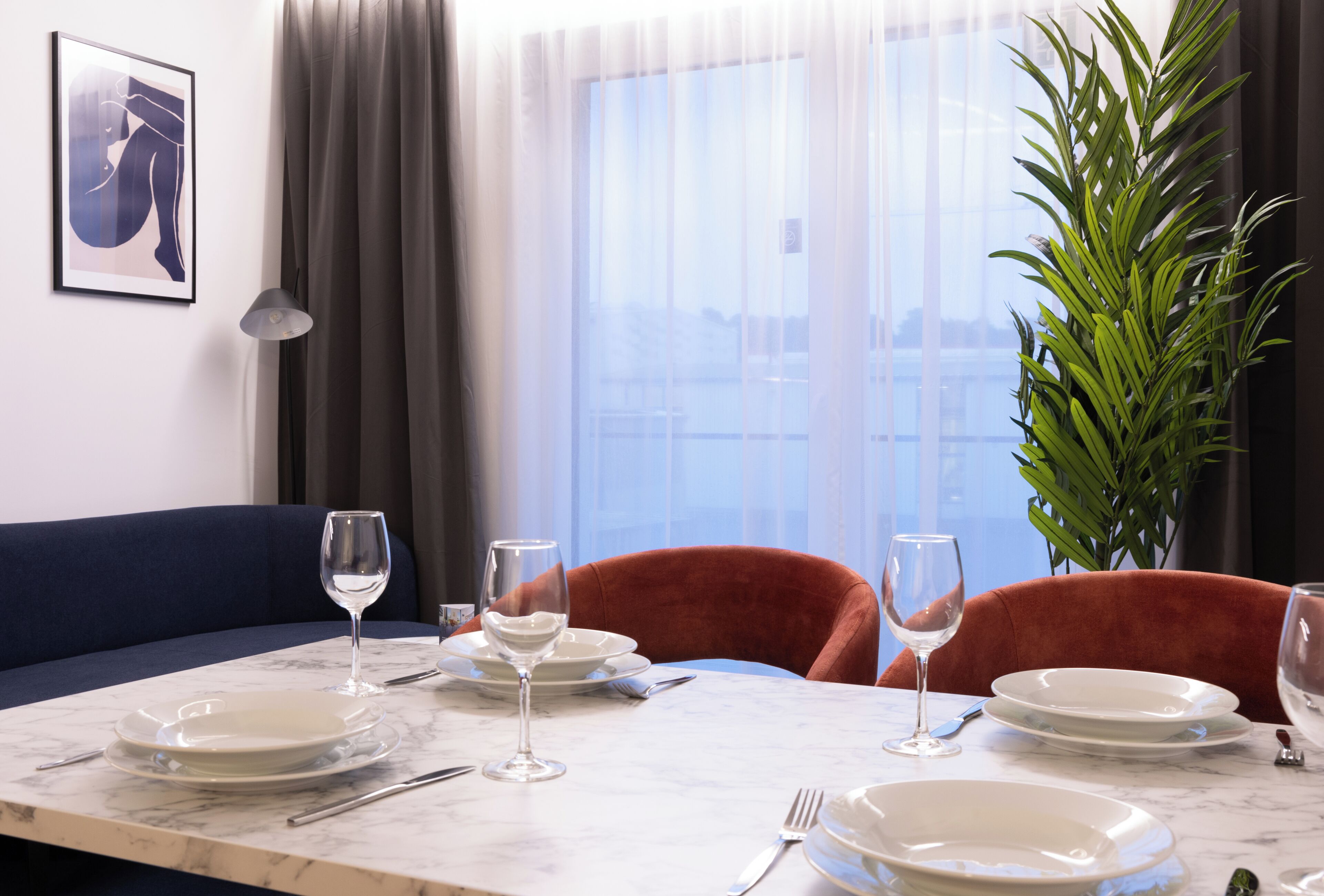 A dining area with a marble table, two chairs, and a potted plant.